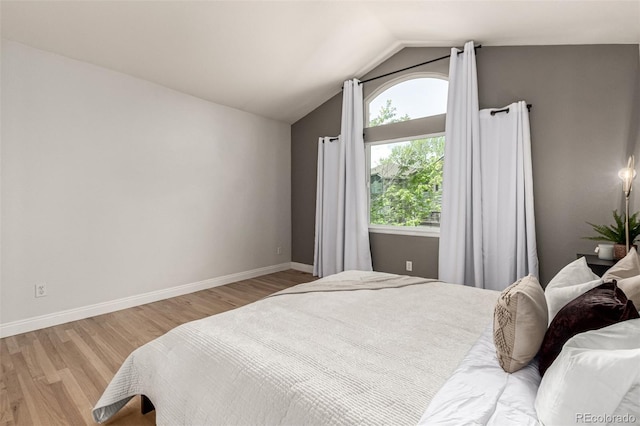 bedroom with wood finished floors, vaulted ceiling, and baseboards