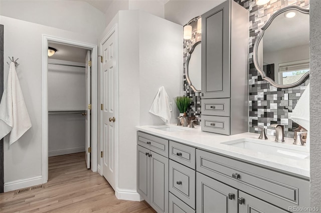 full bathroom with a closet, wood finished floors, double vanity, and baseboards