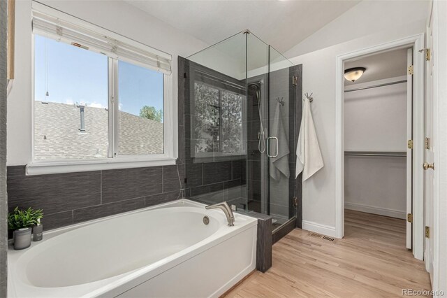 full bathroom with a shower stall, a bath, wood finished floors, vaulted ceiling, and baseboards