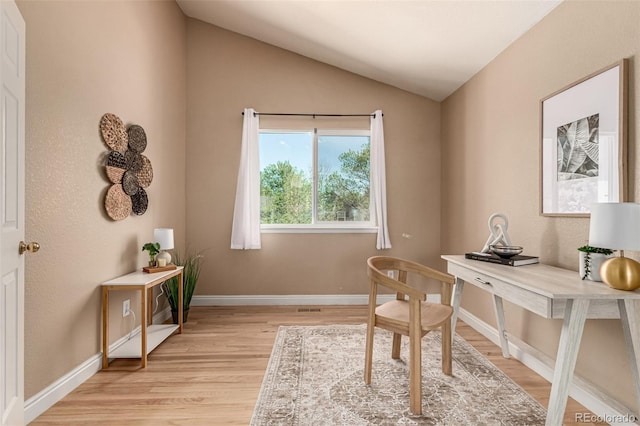 office space with light wood-style floors, lofted ceiling, and baseboards