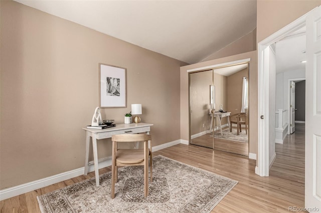 home office with light wood-type flooring, baseboards, and vaulted ceiling