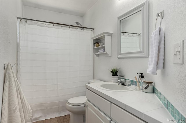 bathroom featuring vanity, wood finished floors, toilet, and a textured wall