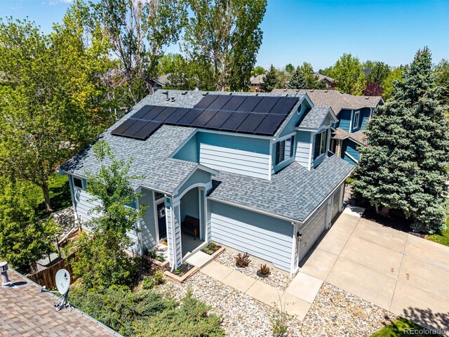 view of front of house featuring a shingled roof, roof mounted solar panels, a porch, and driveway