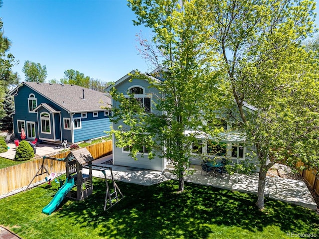 rear view of house with a patio, a playground, and roof with shingles