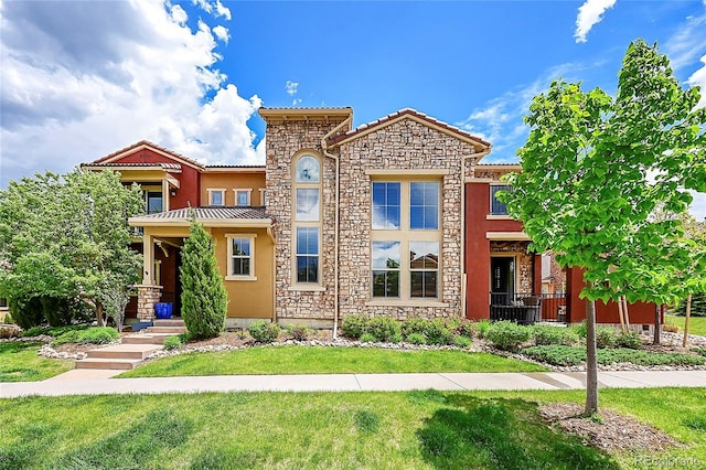 mediterranean / spanish home featuring stone siding, a front yard, a tile roof, and stucco siding