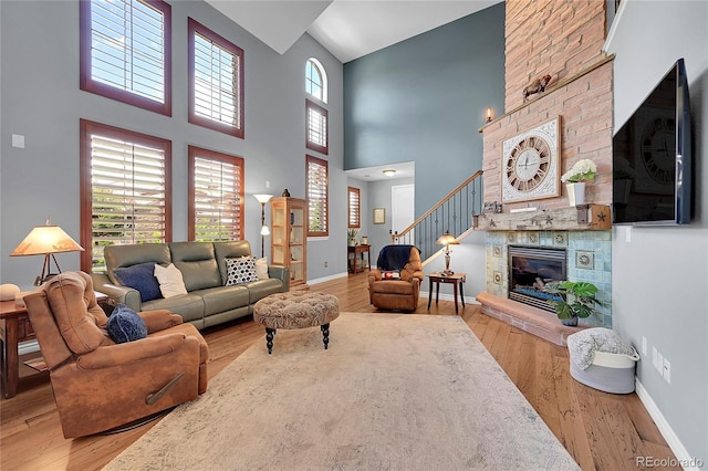 living room with stairway, a fireplace, wood finished floors, and baseboards