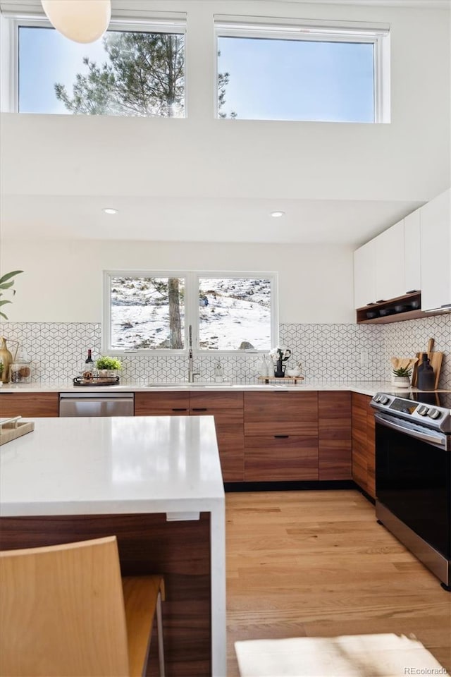 kitchen with appliances with stainless steel finishes, a towering ceiling, a wealth of natural light, and white cabinets