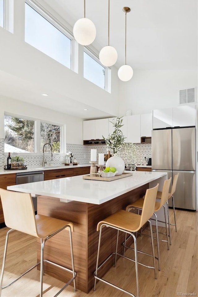 kitchen featuring stainless steel appliances, a center island, pendant lighting, and a kitchen bar