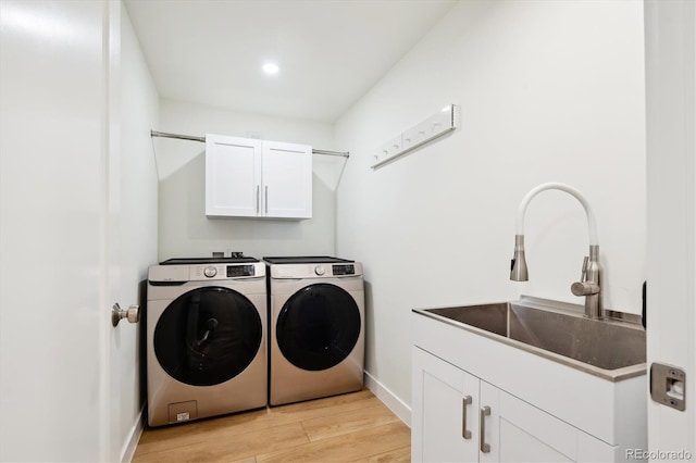 washroom with cabinets, washer and clothes dryer, sink, and light wood-type flooring