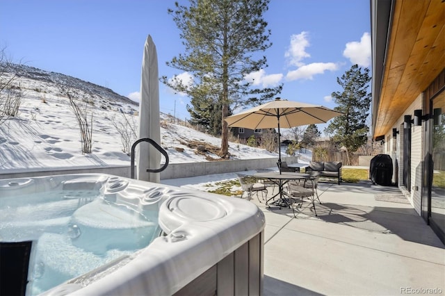 snow covered patio with a mountain view and a hot tub