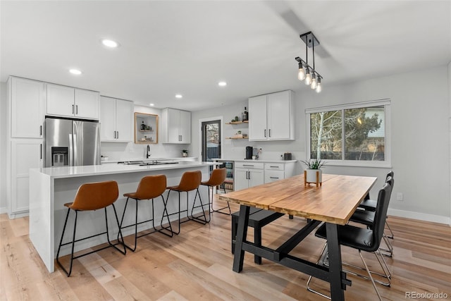 kitchen featuring white cabinetry, stainless steel fridge, a center island, and decorative light fixtures