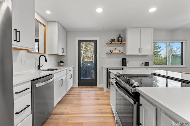 kitchen featuring white cabinetry, stainless steel appliances, light hardwood / wood-style flooring, and sink