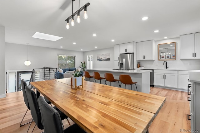 dining space featuring light hardwood / wood-style flooring, sink, and a skylight