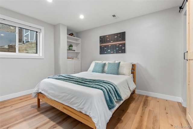 bedroom featuring light hardwood / wood-style flooring and a barn door