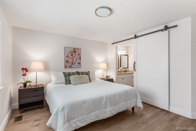 5332 S Lisbon Way, Centennial, CO 80015 - bedroom with a barn door, light wood-style floors, baseboards, a textured ceiling, and a sink
