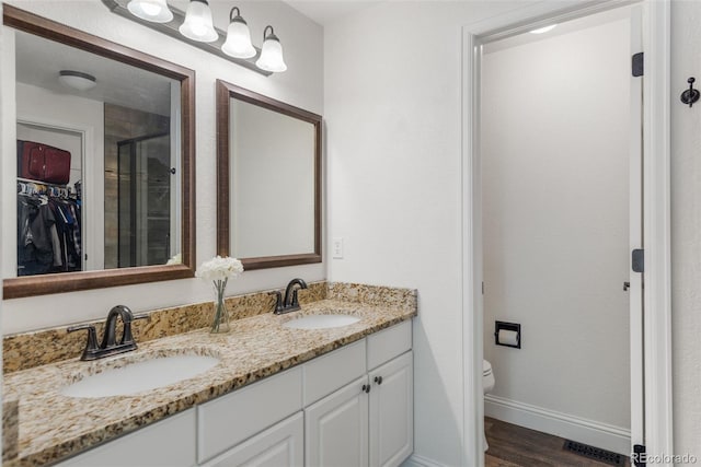 5332 S Lisbon Way, Centennial, CO 80015 - full bath with double vanity, toilet, wood finished floors, a shower stall, and baseboards