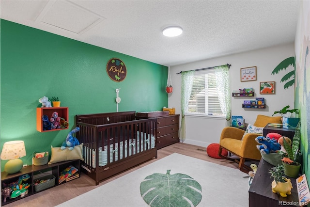 5332 S Lisbon Way, Centennial, CO 80015 - bedroom with a textured ceiling, wood finished floors, a nursery area, baseboards, and attic access