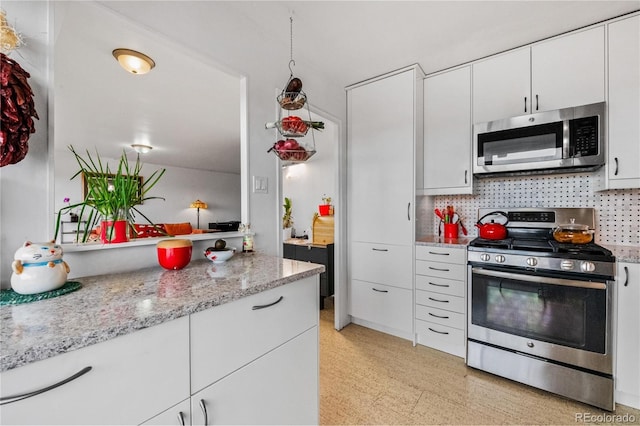 kitchen featuring stainless steel appliances, white cabinets, backsplash, and light stone countertops