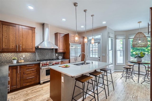 222 S Monroe St, Denver, CO 80209 - kitchen with wall chimney range hood, high end appliances, a sink, brown cabinets, and decorative backsplash