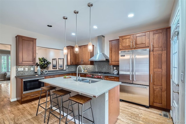 222 S Monroe St, Denver, CO 80209 - kitchen with built in fridge, wall chimney exhaust hood, a sink, black microwave, and light wood-style flooring