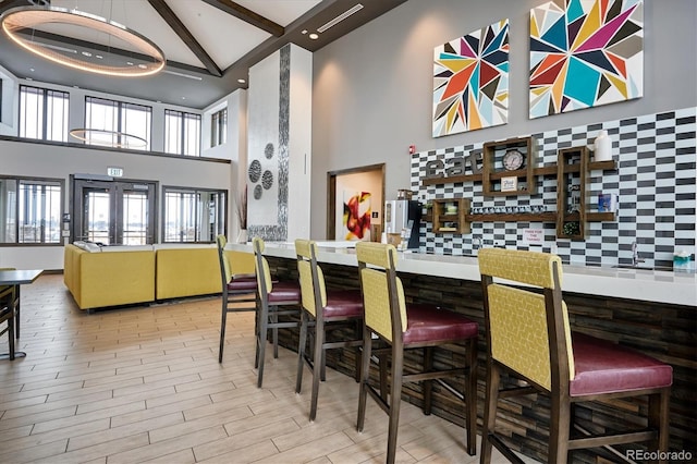 bar featuring beam ceiling, high vaulted ceiling, decorative backsplash, and french doors