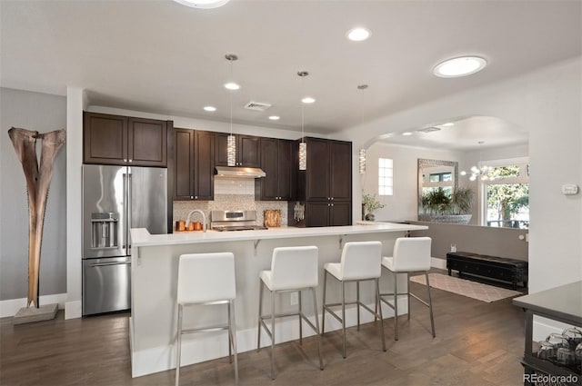 kitchen featuring visible vents, under cabinet range hood, stove, dark brown cabinets, and high end refrigerator