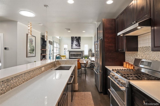 kitchen featuring a sink, light countertops, under cabinet range hood, appliances with stainless steel finishes, and backsplash