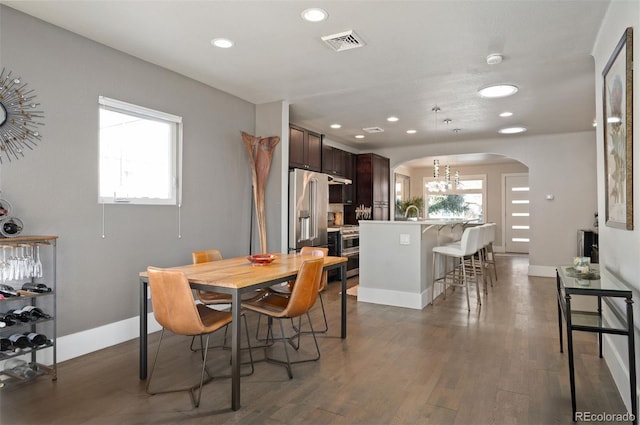 dining space featuring visible vents, arched walkways, baseboards, and dark wood finished floors