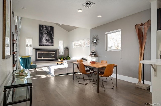 dining room with wood finished floors, visible vents, lofted ceiling, recessed lighting, and a glass covered fireplace