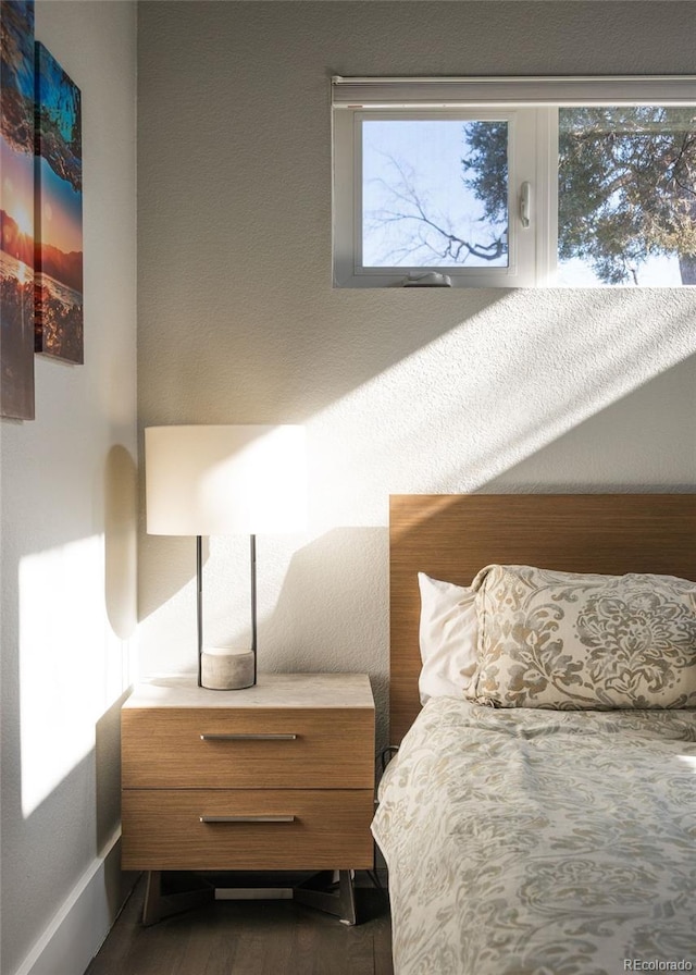 bedroom with a textured wall and dark wood-style flooring