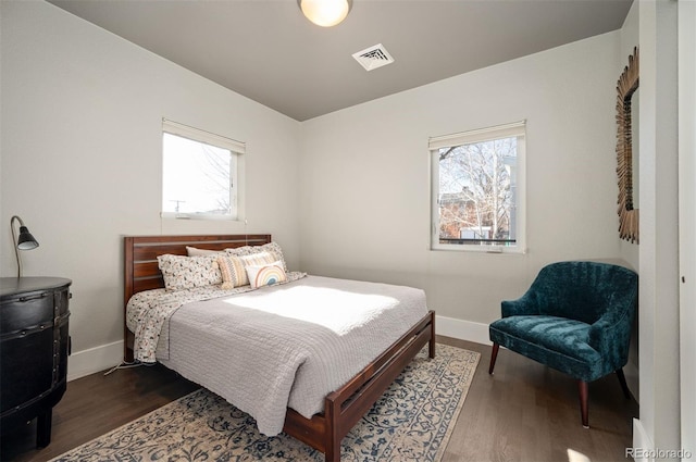 bedroom with dark wood finished floors, visible vents, and baseboards