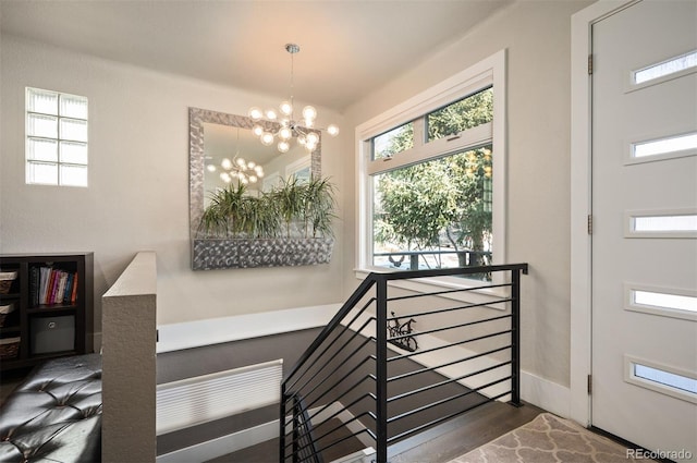 staircase with a notable chandelier and wood finished floors