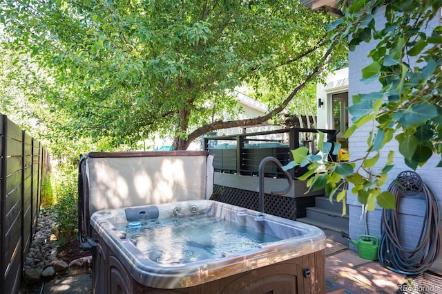 view of patio / terrace with a wooden deck, cooling unit, fence, and a hot tub