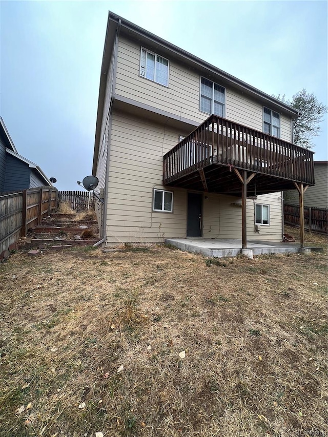 rear view of property featuring a yard, a patio, and a wooden deck