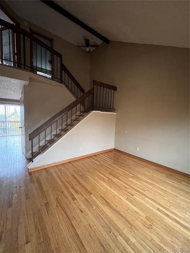 unfurnished living room featuring lofted ceiling with beams, ceiling fan, and light hardwood / wood-style flooring