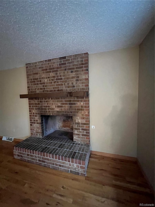 room details with hardwood / wood-style floors, a textured ceiling, and a brick fireplace