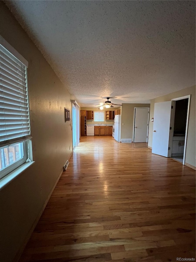 unfurnished living room with hardwood / wood-style floors, a textured ceiling, and ceiling fan