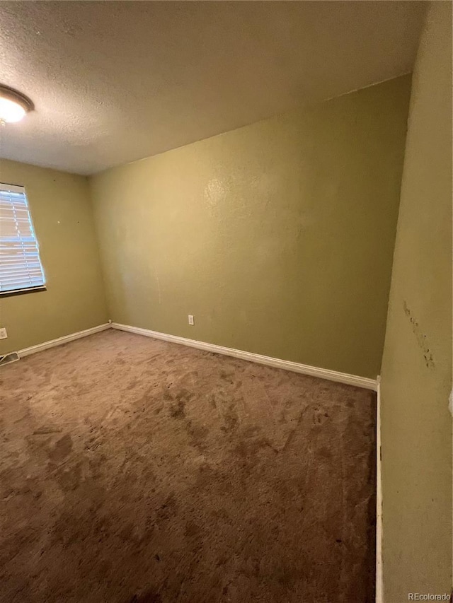 carpeted spare room featuring a textured ceiling