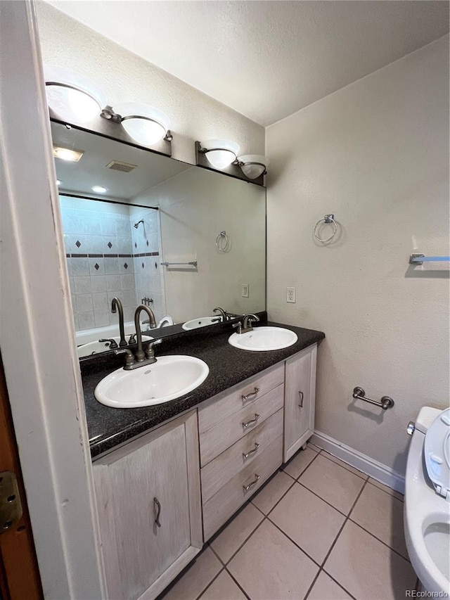 bathroom with tile patterned flooring, vanity, a textured ceiling, and toilet