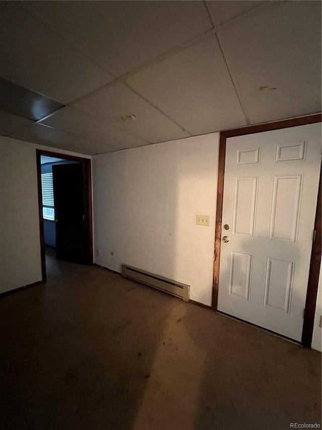 basement featuring a paneled ceiling and a baseboard heating unit