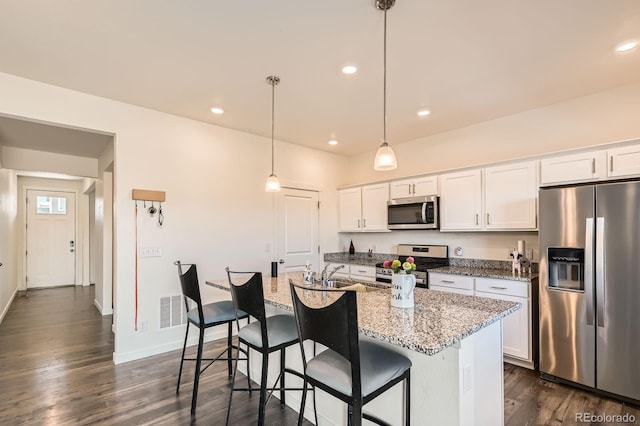 2417 Mountain Sky Dr, Fort Lupton, CO 80621 - kitchen with stainless steel appliances, dark wood-type flooring, white cabinets, an island with sink, and a kitchen breakfast bar
