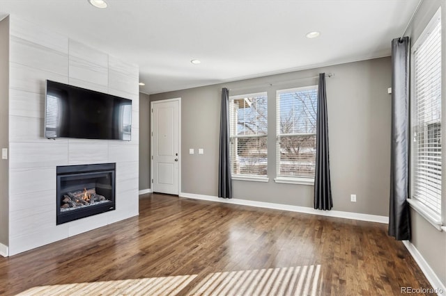 unfurnished living room featuring a tile fireplace and dark hardwood / wood-style flooring