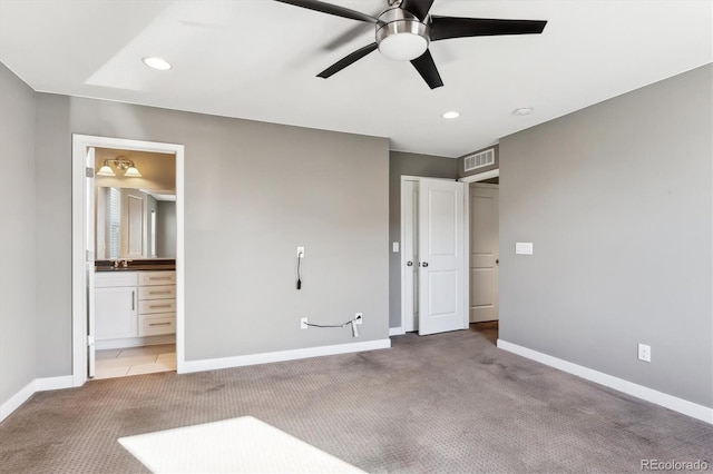 unfurnished bedroom with ceiling fan, ensuite bathroom, and light carpet