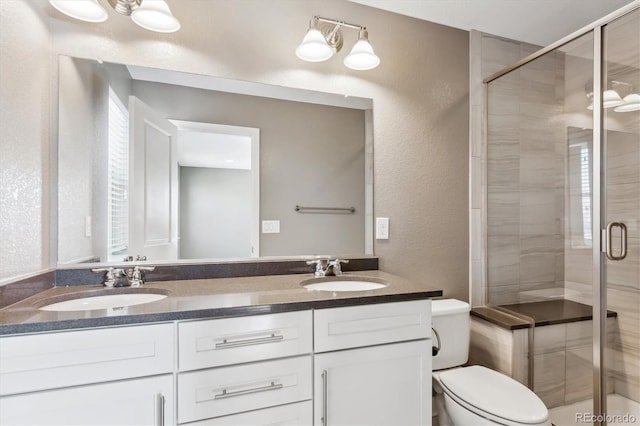 bathroom featuring vanity, a shower with shower door, and toilet