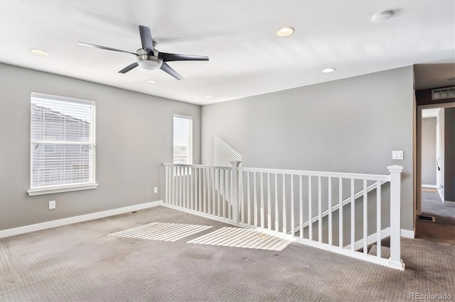 unfurnished room with ceiling fan and carpet