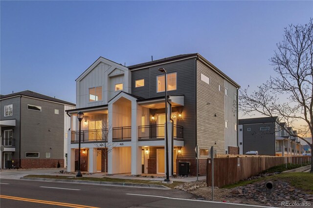 4507-4513 Tabor St, Wheat Ridge, CO 80033 - back of property at dusk featuring a balcony, central AC, fence, and board and batten siding
