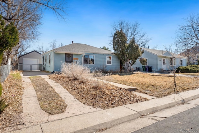 single story home with concrete driveway, an outdoor structure, and fence