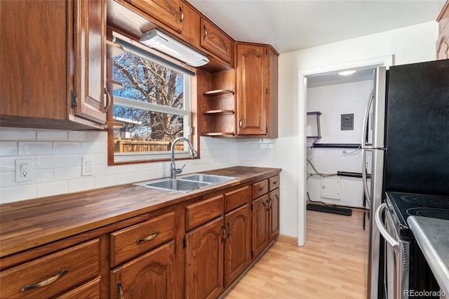 kitchen featuring a sink, tasteful backsplash, wood counters, and light wood-style floors