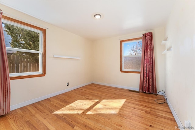 spare room with light wood-style floors, visible vents, and baseboards