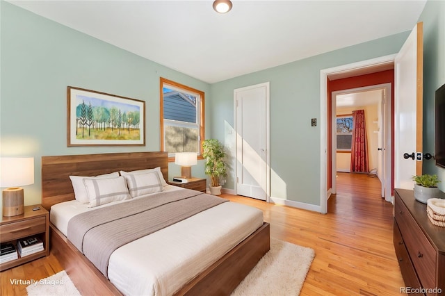 bedroom featuring light wood finished floors, multiple windows, and baseboards